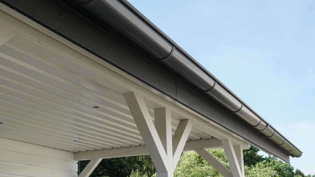 Goot op een carport met golfplaten dak en witte steunbalken.